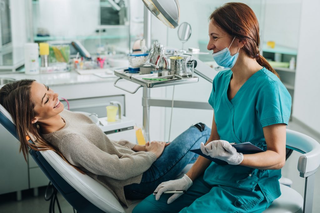 a female dentist sitting next to a patient in a dental exam chair