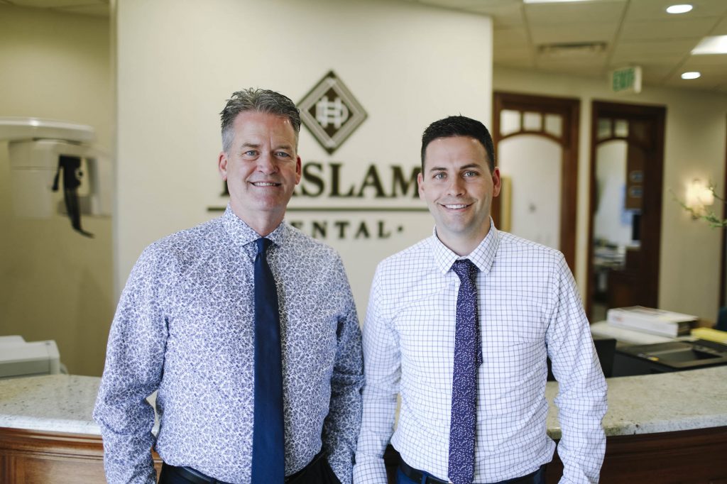 portrait of dr jeffery haslam and dr jacob haslam at the front desk of haslam dental, a dentist office in ogden utah