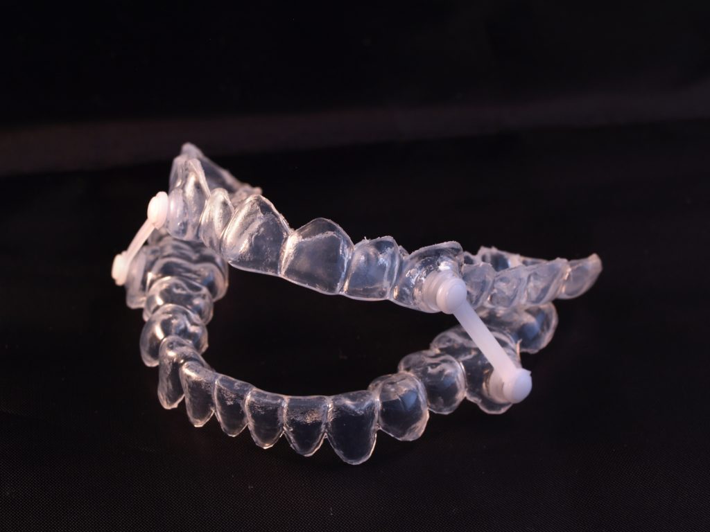 clear sleep apnea dental appliance on black ground