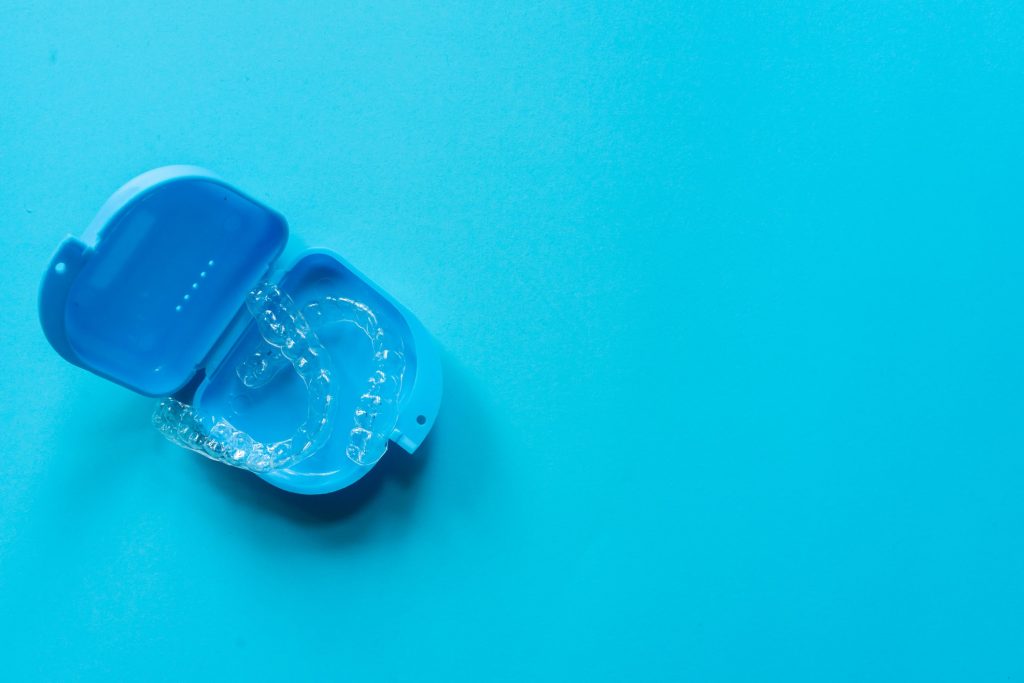 clear teeth aligners sitting in a blue container on a blue background