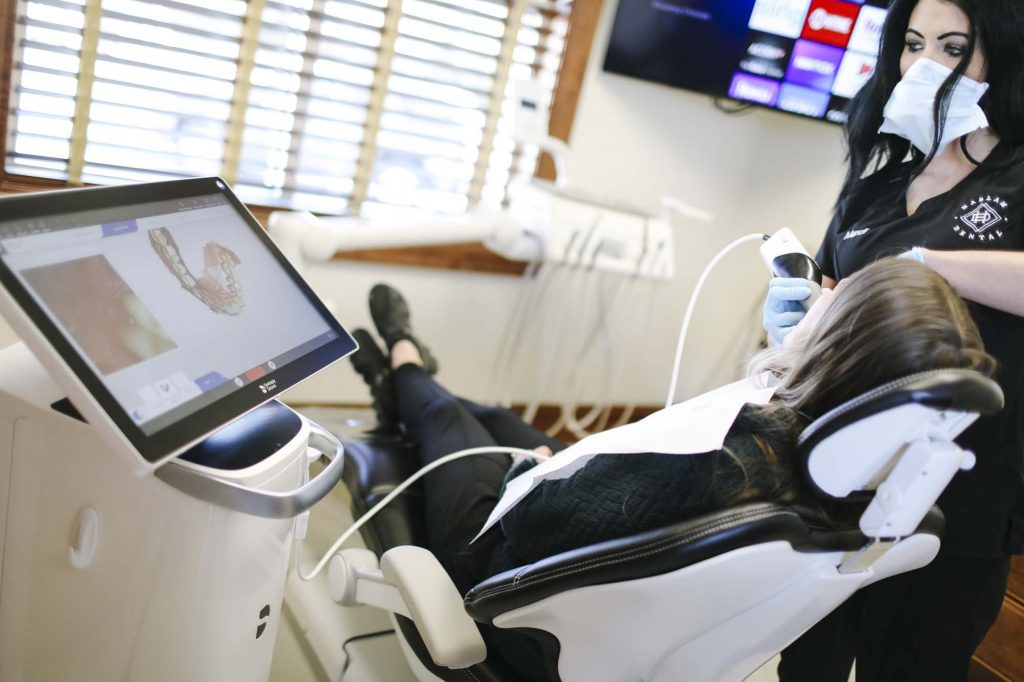 a female dental assistant uses an intraoral camera to see a 3-d model of the patients teeth